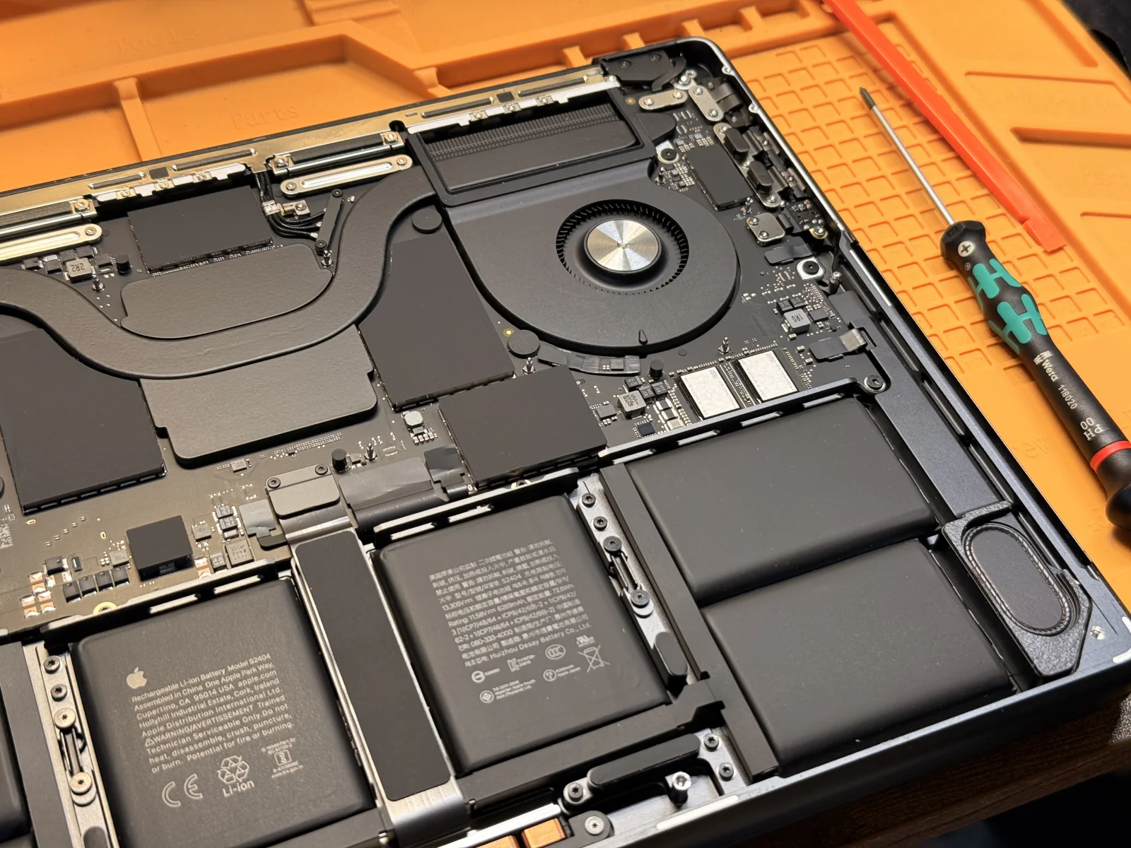Open MacBook on an orange repair mat during an internal hardware repair